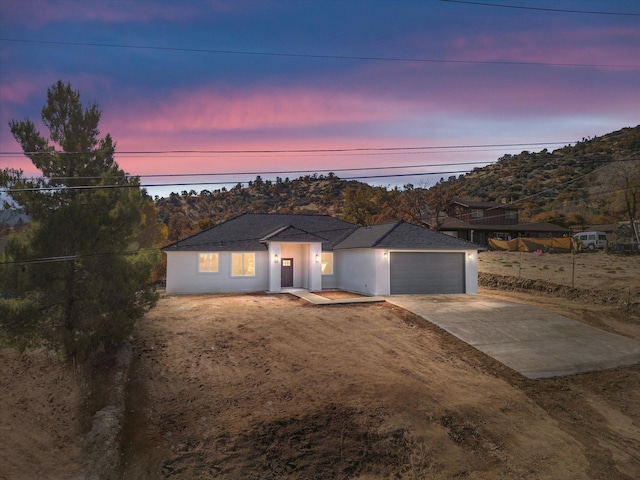 single story home featuring a garage, concrete driveway, and stucco siding