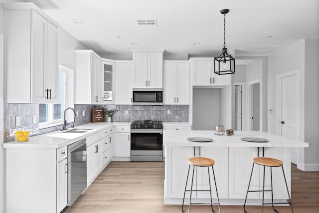 kitchen featuring visible vents, decorative backsplash, a breakfast bar area, appliances with stainless steel finishes, and a sink