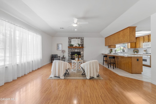 22401 Citation St, Tehachapi, CA 93561 - living room featuring light wood-style flooring, a ceiling fan, a fireplace, and lofted ceiling