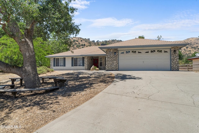 22401 Citation St, Tehachapi, CA 93561 - ranch-style house featuring driveway, a garage, and stone siding