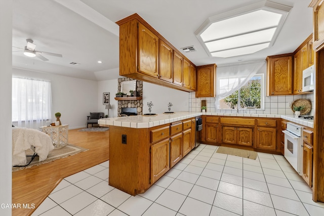 22401 Citation St, Tehachapi, CA 93561 - kitchen with open floor plan, brown cabinets, a peninsula, decorative backsplash, and a stone fireplace
