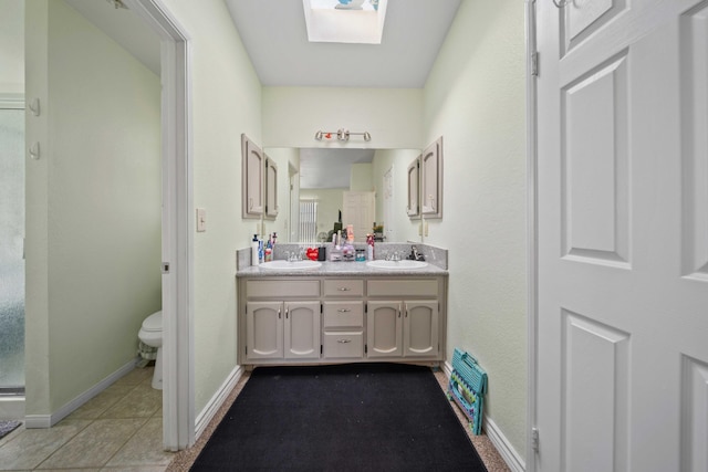 bathroom with tile patterned flooring, vanity, a skylight, and toilet