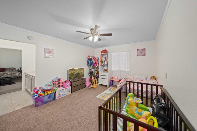 carpeted bedroom featuring crown molding, ceiling fan, and a crib