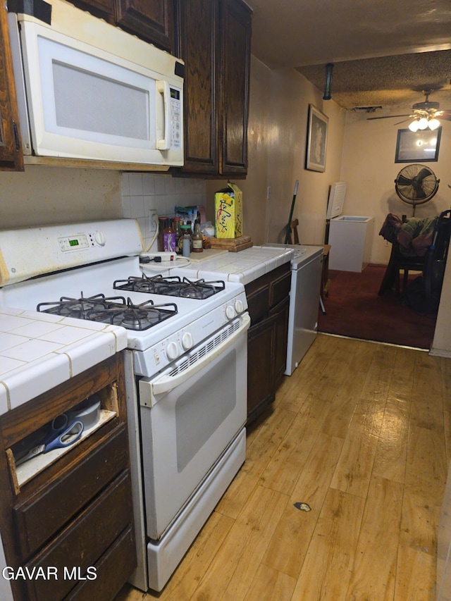 1239 W Rosecrans Ave Unit 31, Gardena, CA 90247 - kitchen with white appliances, tile counters, dark brown cabinets, light wood-type flooring, and a ceiling fan