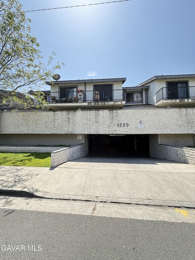 1239 W Rosecrans Ave Unit 31, Gardena, CA 90247 - view of front facade featuring an attached garage, concrete driveway, stucco siding, and a balcony
