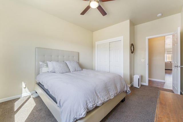 carpeted bedroom with a closet, baseboards, and a ceiling fan