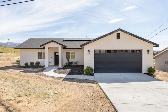 modern inspired farmhouse with stucco siding, a garage, solar panels, driveway, and roof with shingles