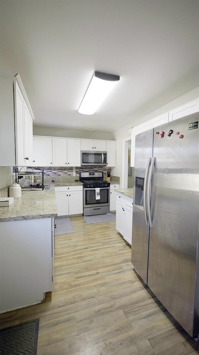 kitchen featuring white cabinets, appliances with stainless steel finishes, and light stone countertops