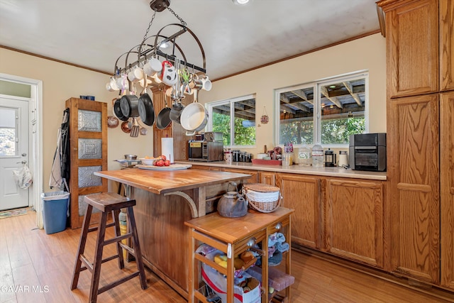 24750 Flatiron Ct, Tehachapi, CA 93561 - kitchen with butcher block counters, ornamental molding, light wood-style flooring, brown cabinets, and a chandelier