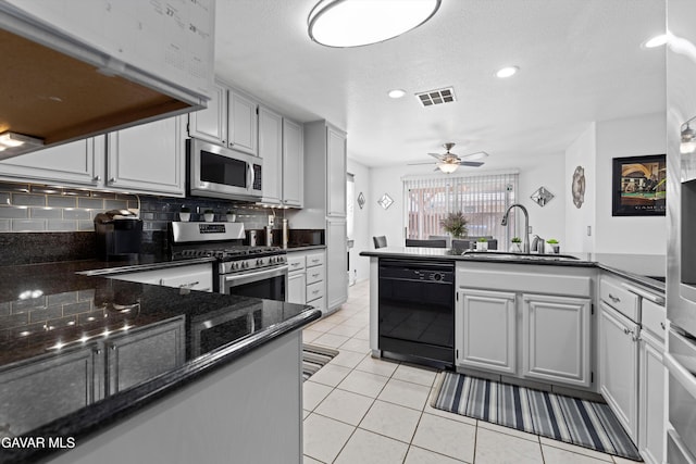 3267 Desert Cloud Ave, Rosamond, CA 93560 - kitchen featuring appliances with stainless steel finishes, a peninsula, a ceiling fan, light tile patterned floors, and dark stone countertops