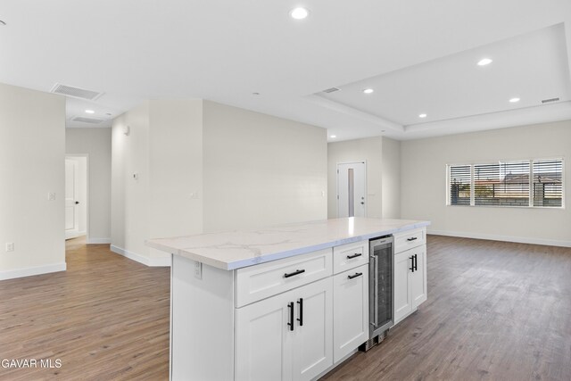 9207 Margery Ave, California City, CA 93505 - kitchen featuring beverage cooler, light wood-style floors, a kitchen island, white cabinetry, and light stone countertops