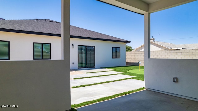 9207 Margery Ave, California City, CA 93505 - back of property featuring a patio area, a putting green, roof with shingles, and stucco siding