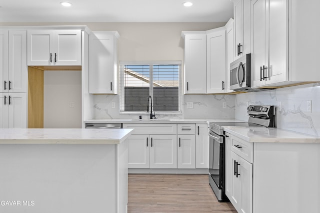 9207 Margery Ave, California City, CA 93505 - kitchen featuring stainless steel appliances, recessed lighting, white cabinetry, decorative backsplash, and light wood-style floors