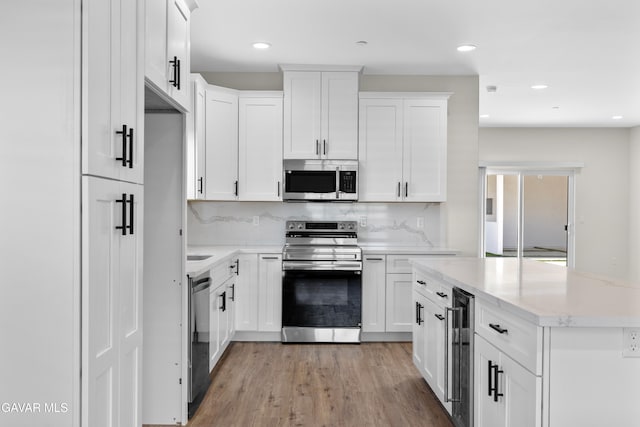 9207 Margery Ave, California City, CA 93505 - kitchen featuring appliances with stainless steel finishes, wine cooler, light wood-style floors, white cabinets, and recessed lighting