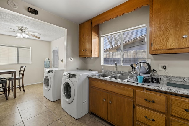 clothes washing area with sink, a textured ceiling, ceiling fan, light tile patterned floors, and washing machine and dryer