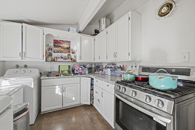 kitchen featuring independent washer and dryer, light stone countertops, stainless steel range with gas cooktop, sink, and white cabinetry