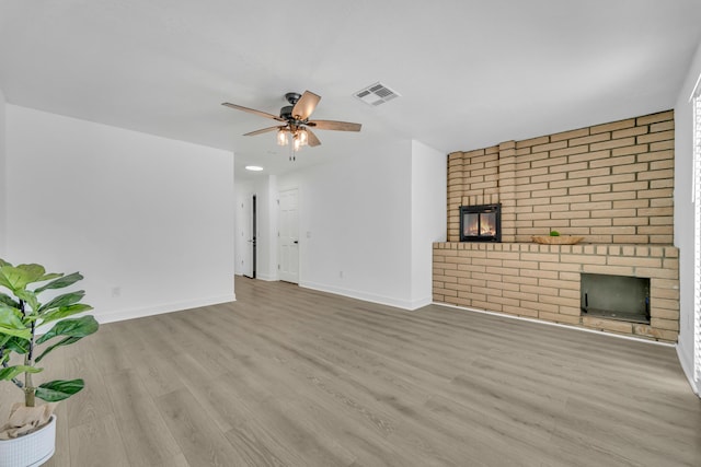 unfurnished living room featuring a brick fireplace, light hardwood / wood-style flooring, and ceiling fan