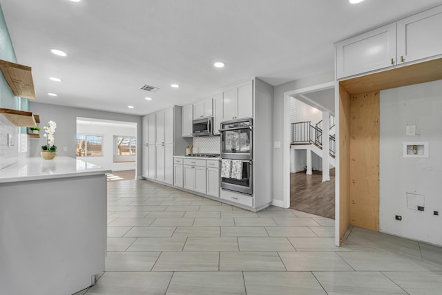 kitchen featuring stainless steel appliances, white cabinetry, and decorative backsplash