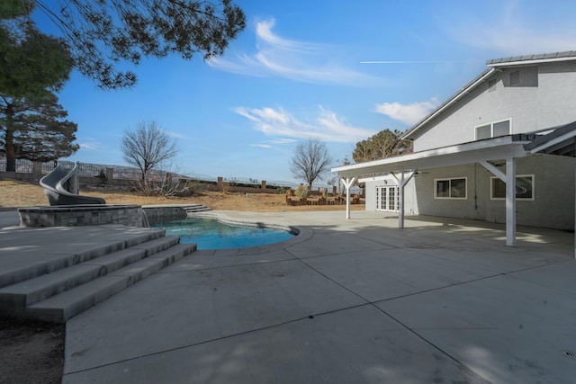 view of swimming pool with a water slide, a patio area, and french doors