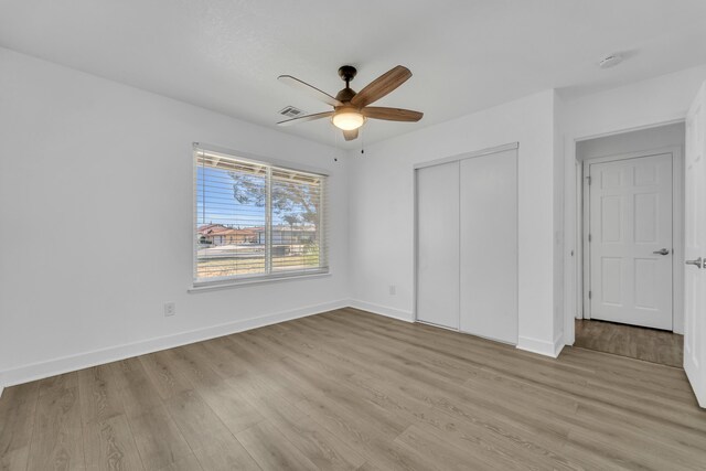 unfurnished bedroom featuring light hardwood / wood-style floors, a closet, and ceiling fan