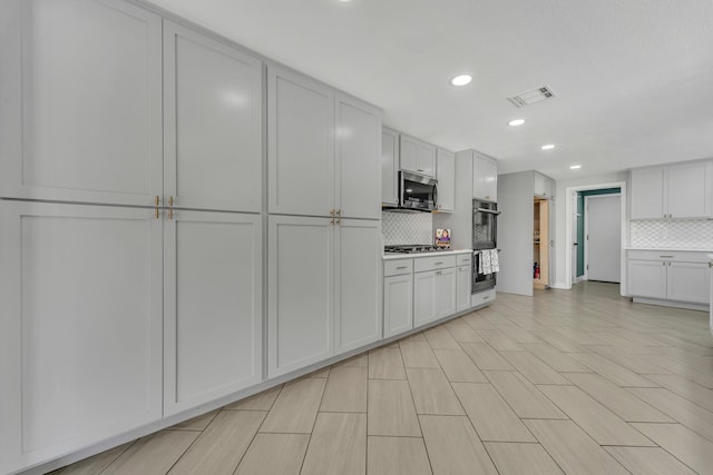 kitchen with appliances with stainless steel finishes, white cabinets, and decorative backsplash