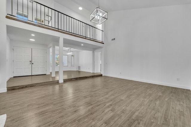 unfurnished living room featuring hardwood / wood-style flooring, a chandelier, and a high ceiling