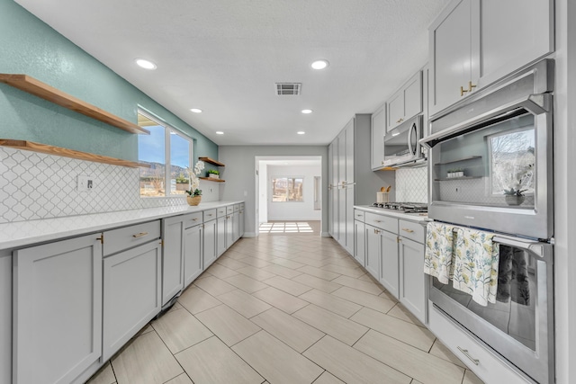 kitchen with appliances with stainless steel finishes, decorative backsplash, and gray cabinetry