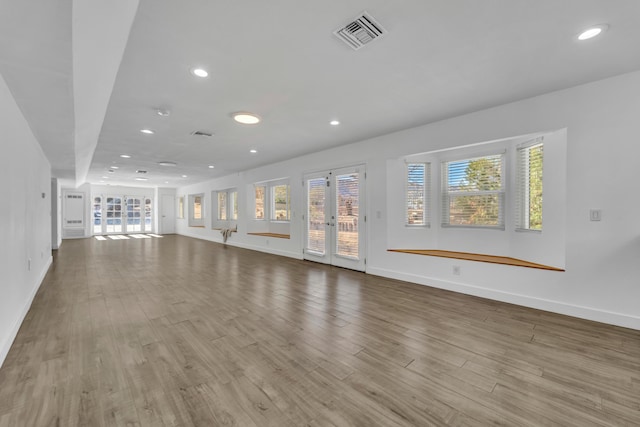 unfurnished living room featuring french doors and light hardwood / wood-style flooring