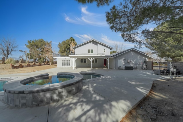 rear view of property with a swimming pool with hot tub and a patio