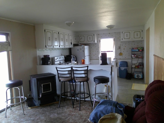 kitchen featuring sink, kitchen peninsula, stove, white fridge, and a breakfast bar area