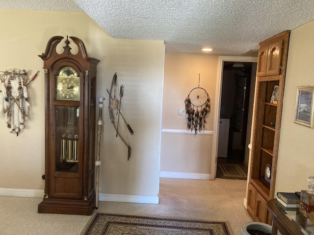 corridor featuring light carpet and a textured ceiling