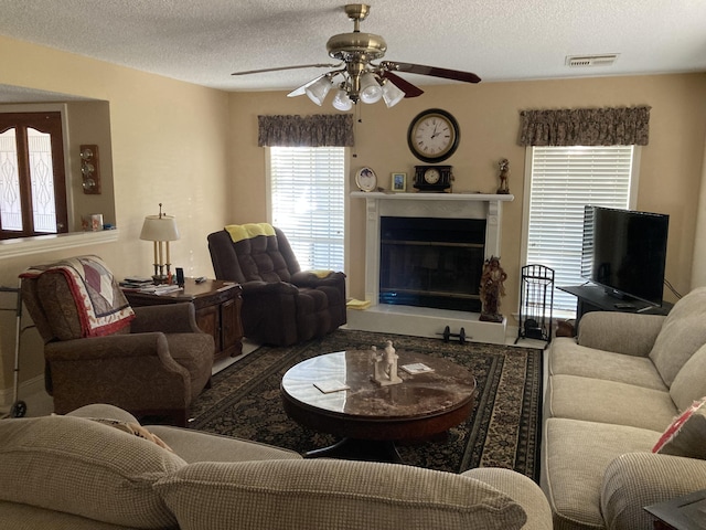 living room featuring ceiling fan and a textured ceiling