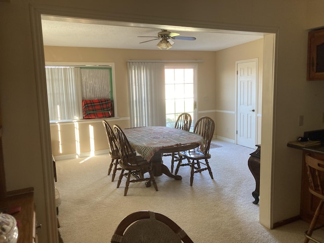 carpeted dining space with ceiling fan