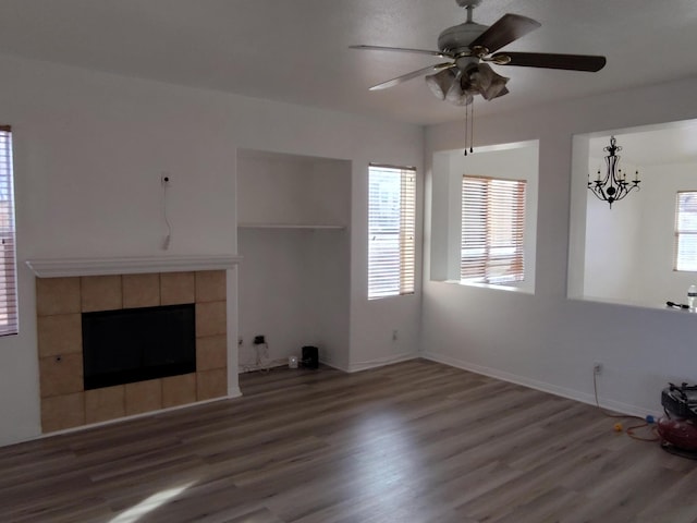 unfurnished living room with a healthy amount of sunlight, wood finished floors, and a tile fireplace