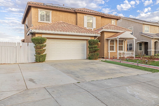 mediterranean / spanish-style home with stucco siding, concrete driveway, an attached garage, fence, and a tiled roof