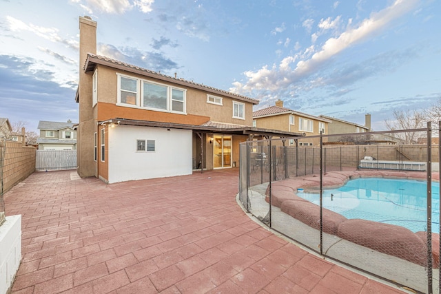 back of property with a patio, a chimney, a fenced backyard, and stucco siding
