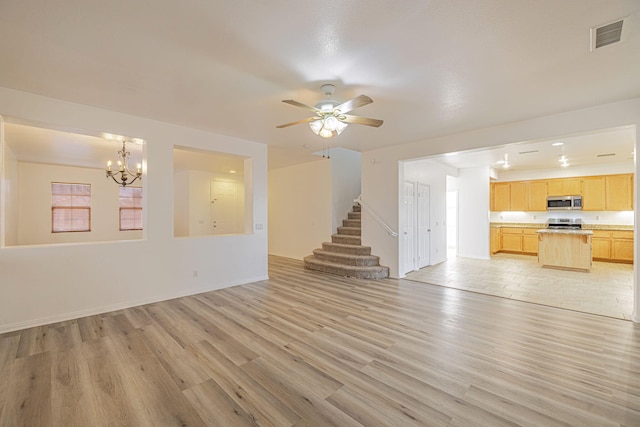 unfurnished living room featuring light wood finished floors, stairs, visible vents, and ceiling fan with notable chandelier