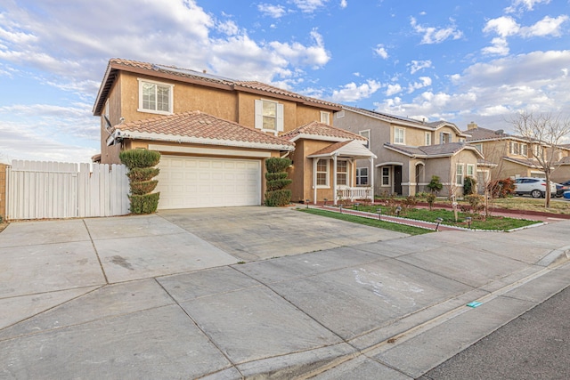 mediterranean / spanish-style home with concrete driveway, a residential view, a tiled roof, fence, and stucco siding