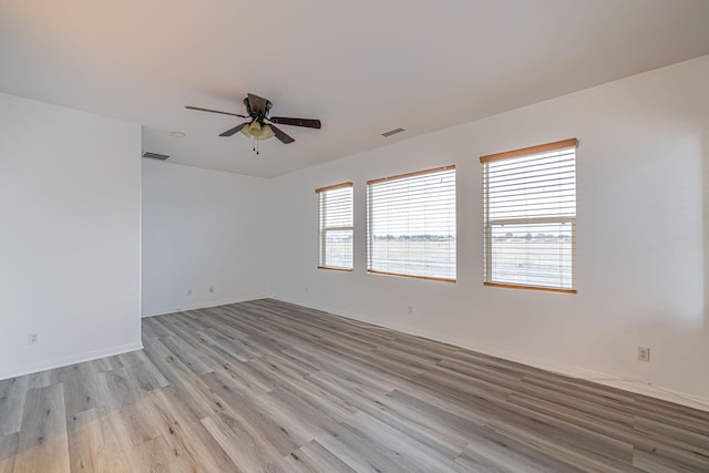 unfurnished room featuring light wood finished floors, baseboards, visible vents, and a ceiling fan