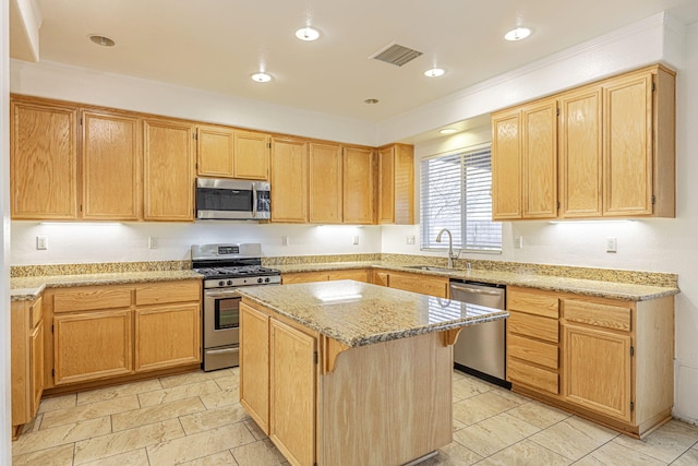 kitchen featuring visible vents, appliances with stainless steel finishes, a center island, light stone countertops, and a sink