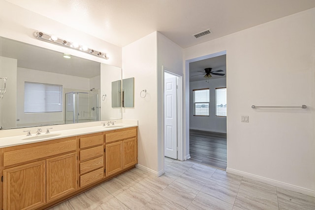 bathroom with double vanity, a shower stall, visible vents, and a sink