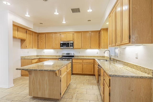 kitchen with visible vents, a kitchen island, appliances with stainless steel finishes, light stone countertops, and a sink