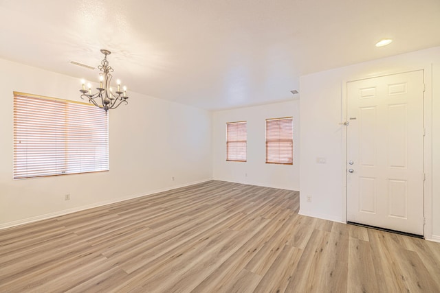 interior space featuring baseboards, an inviting chandelier, visible vents, and light wood-style floors