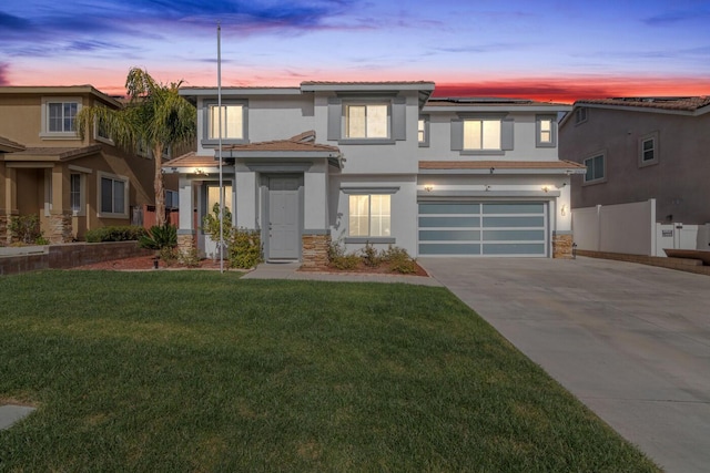 view of front of house with fence, stone siding, concrete driveway, stucco siding, and a front lawn