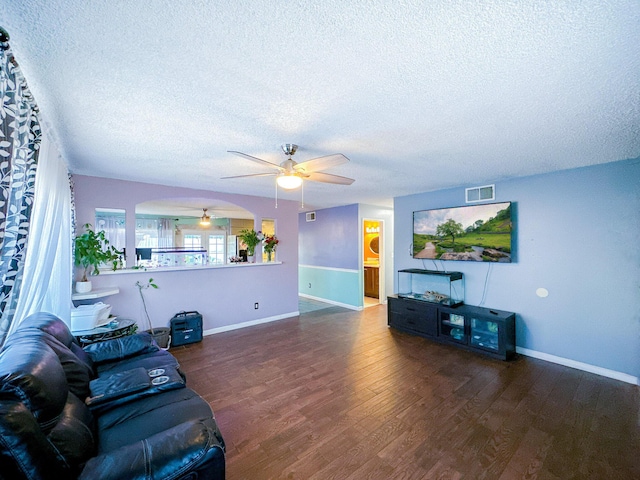 living room featuring ceiling fan, dark wood-type flooring, and a textured ceiling