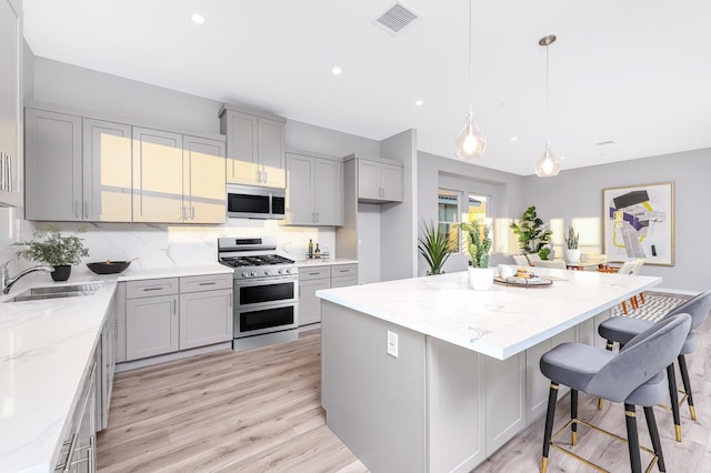 40127 Pevero Ct, Palmdale, CA 93551 - kitchen with appliances with stainless steel finishes, gray cabinetry, light wood-style flooring, light stone counters, and recessed lighting