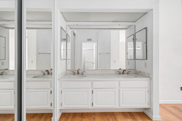 bathroom with double vanity, wood finished floors, and a sink