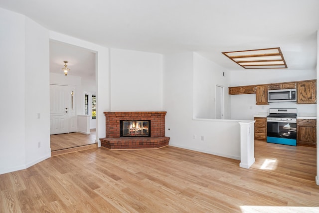 unfurnished living room with lofted ceiling, a fireplace, light wood-style flooring, and baseboards