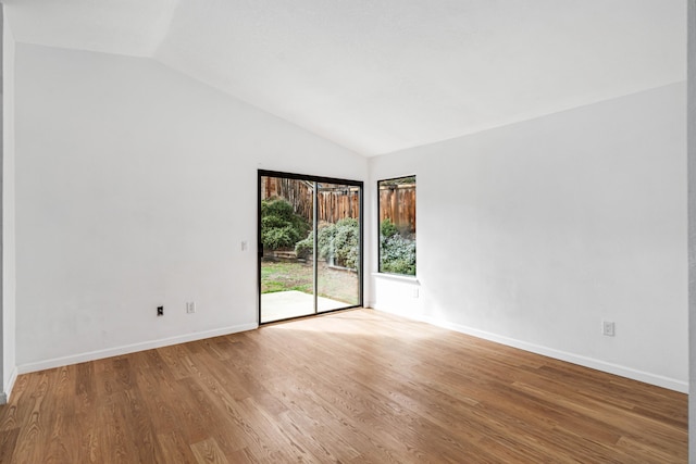 unfurnished room featuring lofted ceiling, baseboards, and wood finished floors