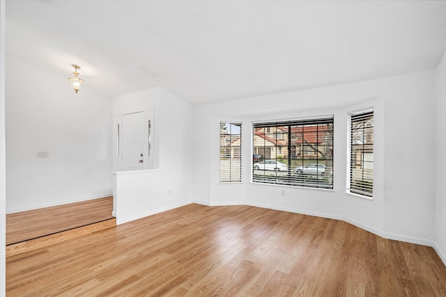 spare room with baseboards and light wood-style floors